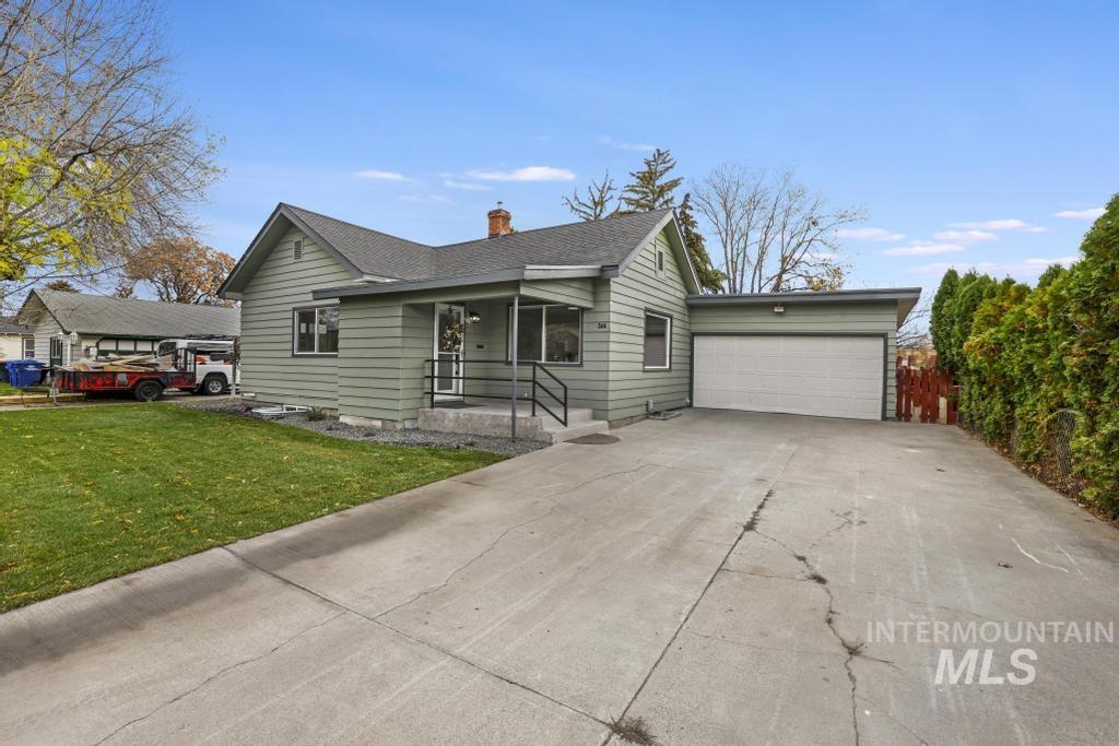 Single story home featuring a chimney, driveway, a front yard, a shingled roof, and a garage