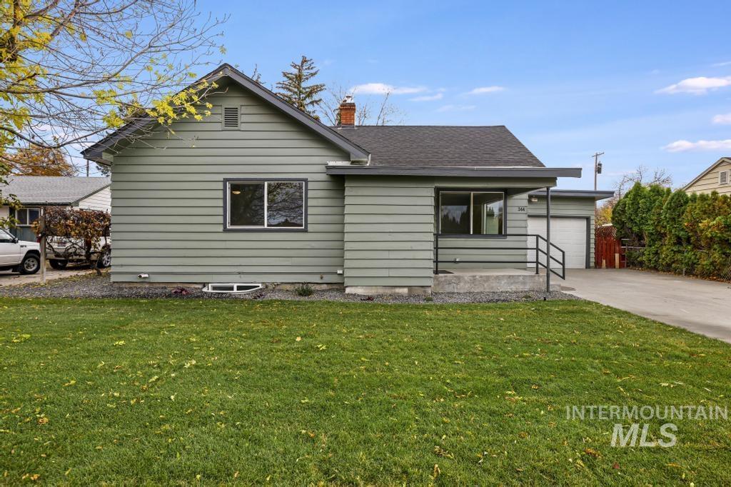 View of front of home with a front yard, a chimney, concrete driveway, and roof with shingles