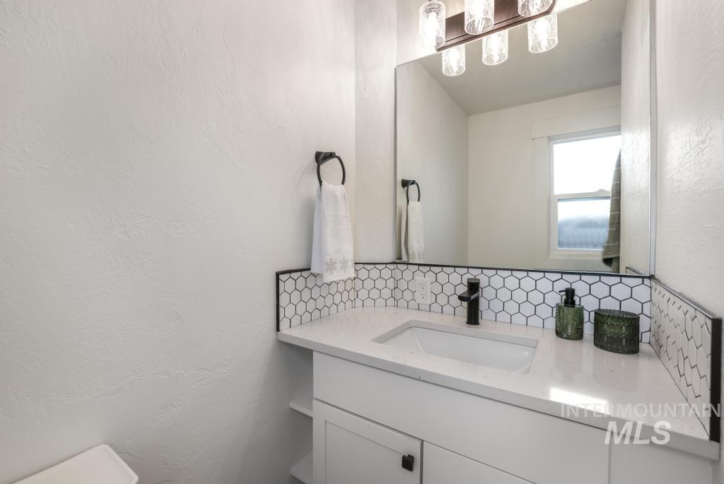 Bathroom with a textured wall, vanity, and decorative backsplash