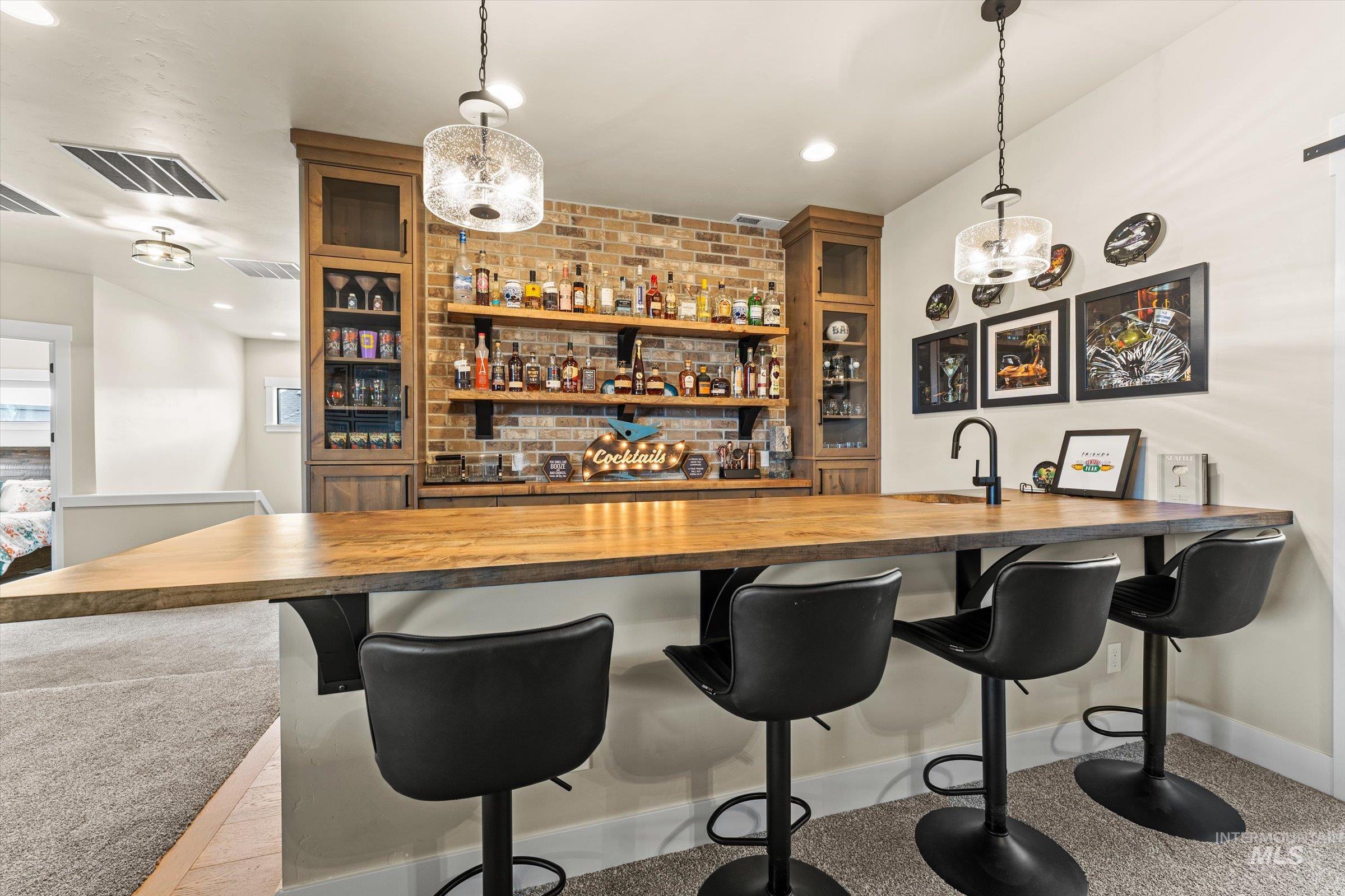 Indoor wet bar featuring wood counters, glass insert cabinets, hanging lights, and open shelves