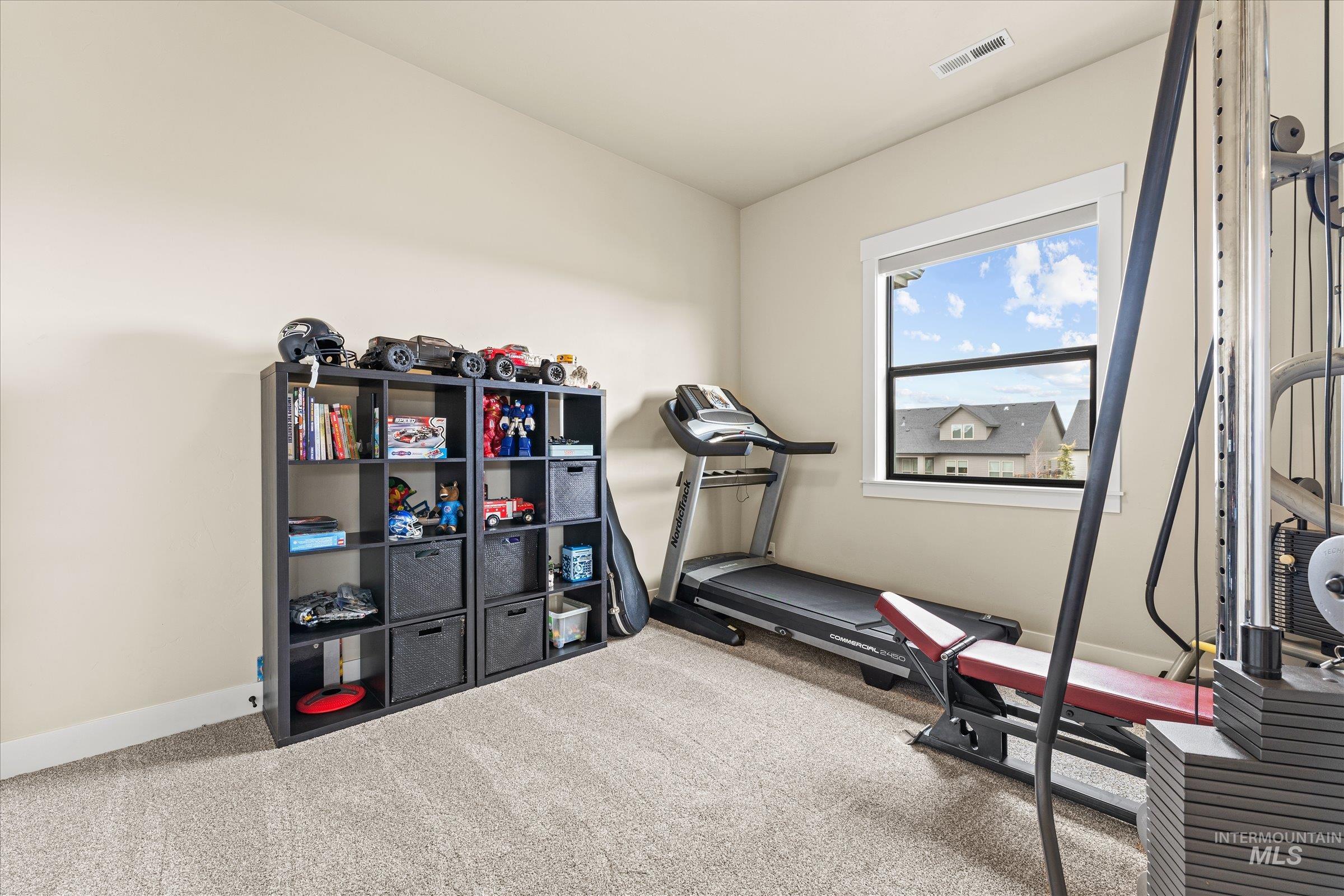 Workout area featuring light colored carpet and baseboards