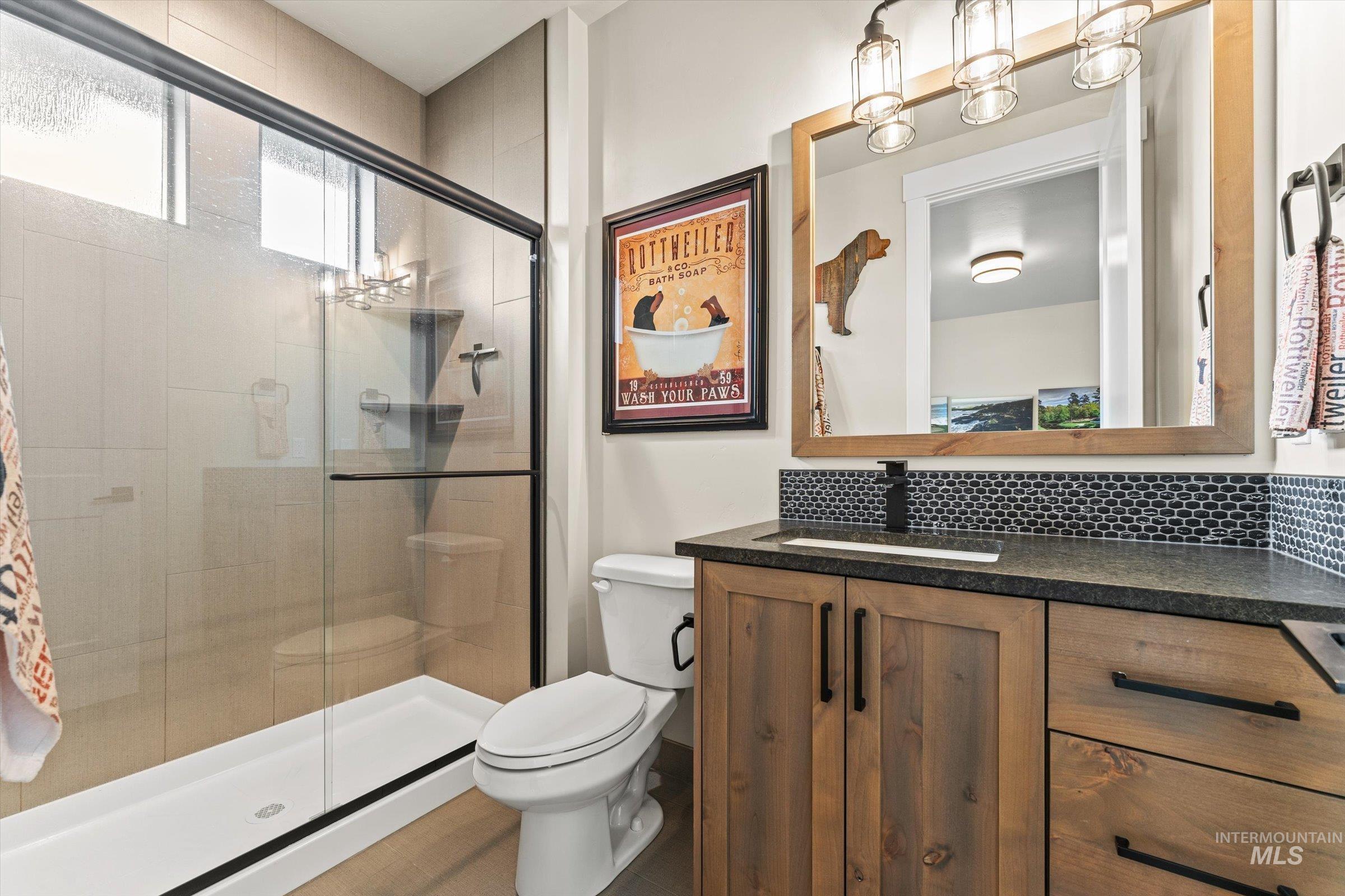 Full bathroom with vanity, a shower stall, and decorative backsplash