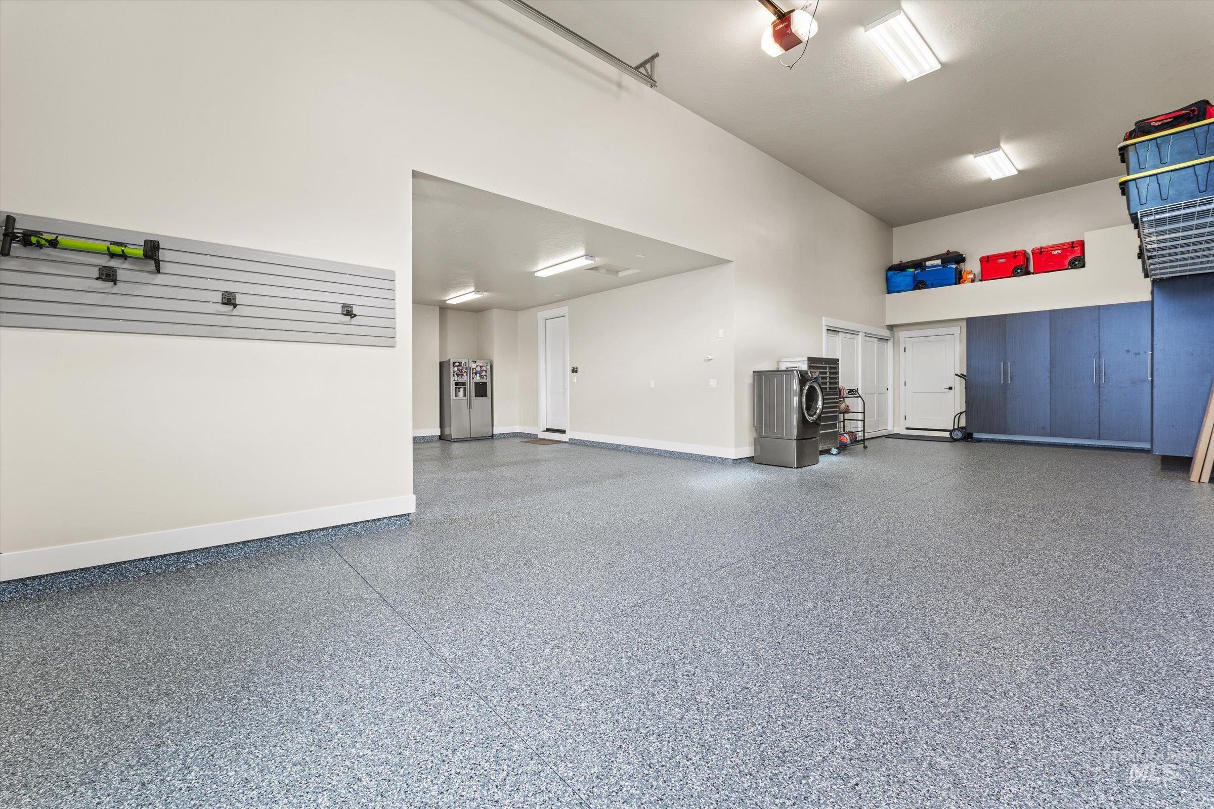 Garage featuring stainless steel fridge with ice dispenser and a garage door opener
