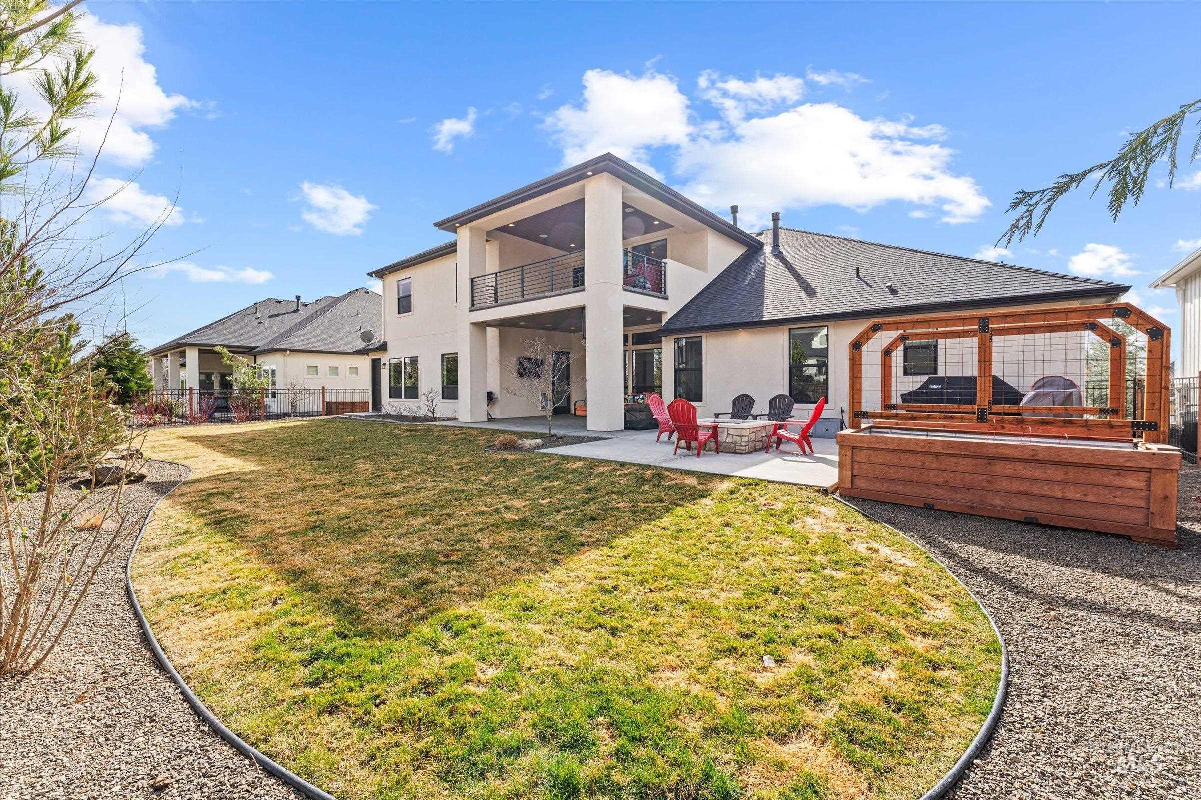 Rear view of property with a fenced backyard, a patio, an outdoor fire pit, stucco siding, and a balcony
