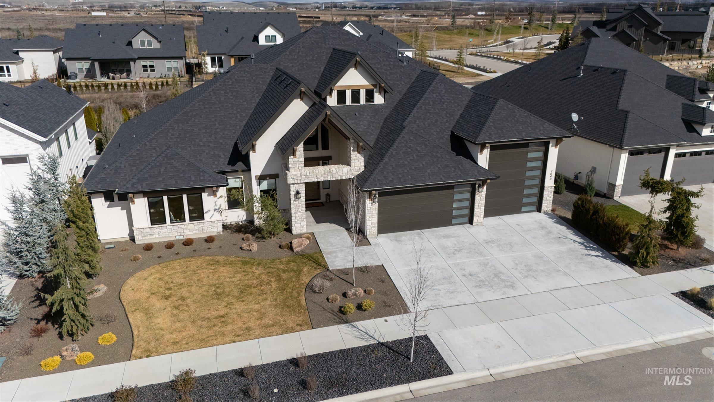 View of front of property with stone siding, a residential view, a garage, and a shingled roof