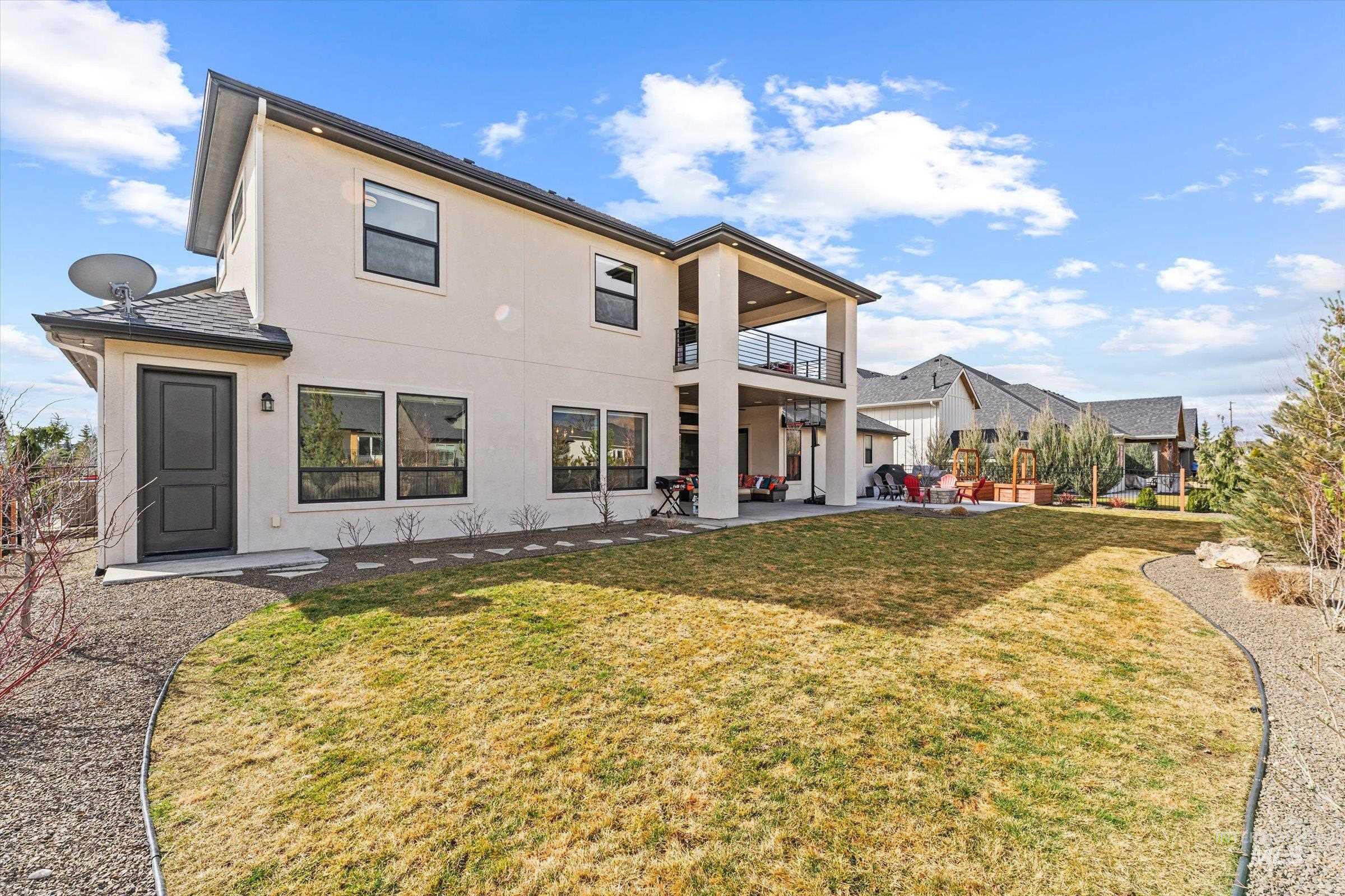 Rear view of house featuring a patio area, stucco siding, a balcony, and a yard
