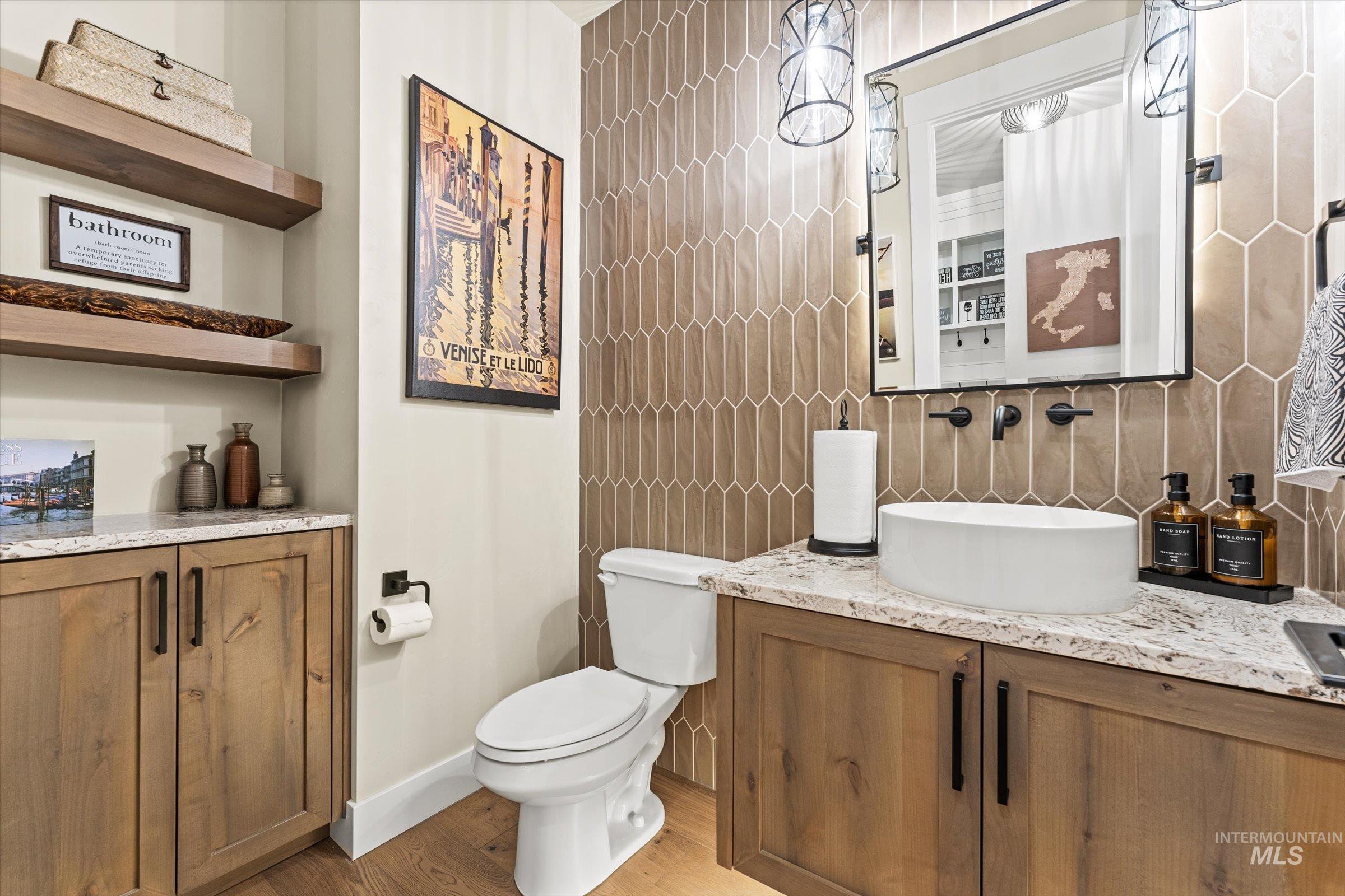 Half bathroom featuring vanity, light wood-type flooring, and tile walls