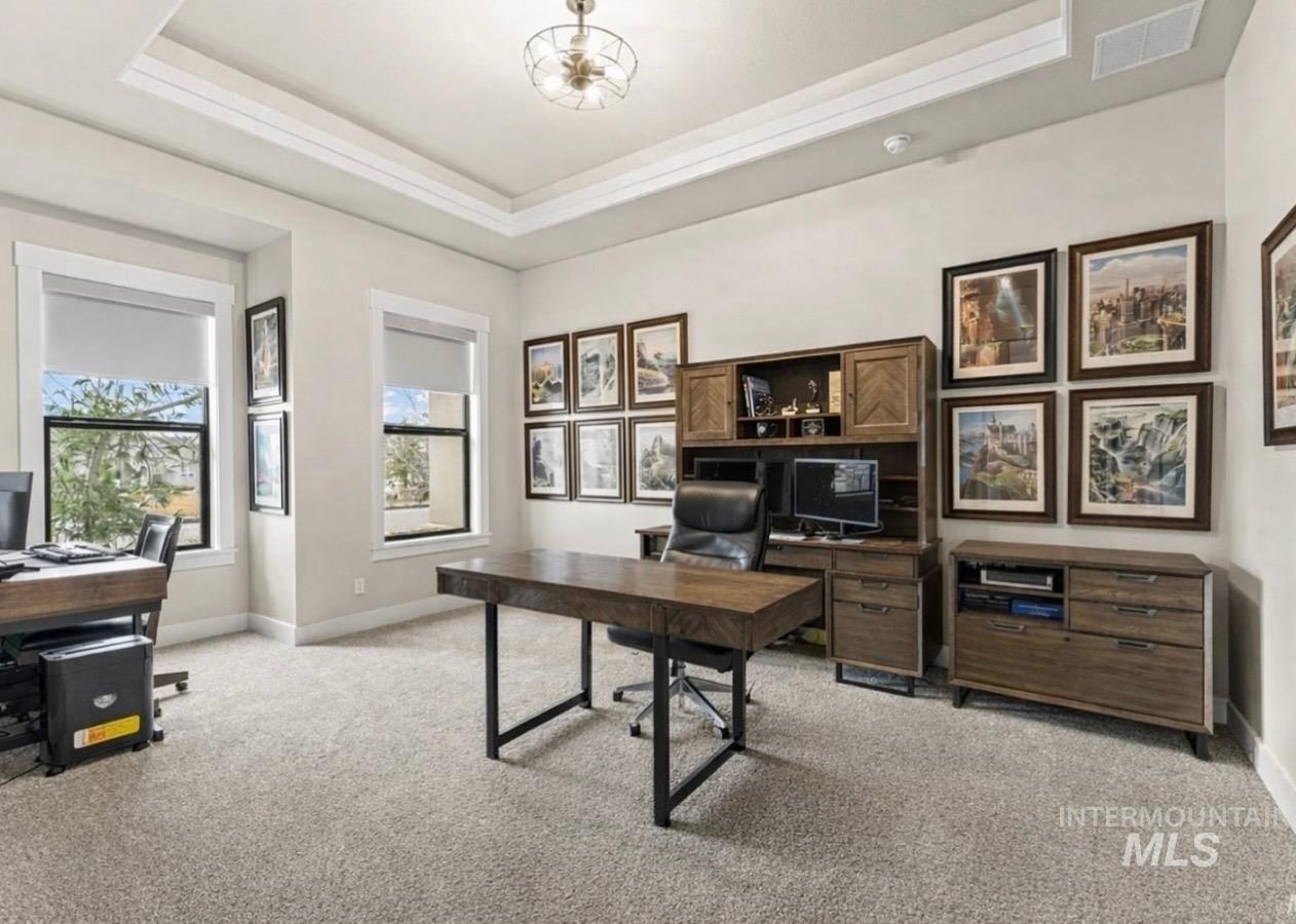 Office space with a tray ceiling and light colored carpet