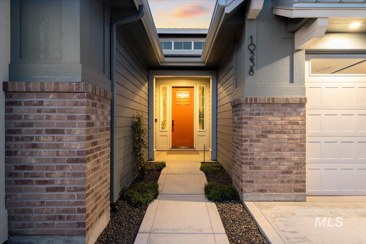 Exterior entry at dusk with brick siding and a garage