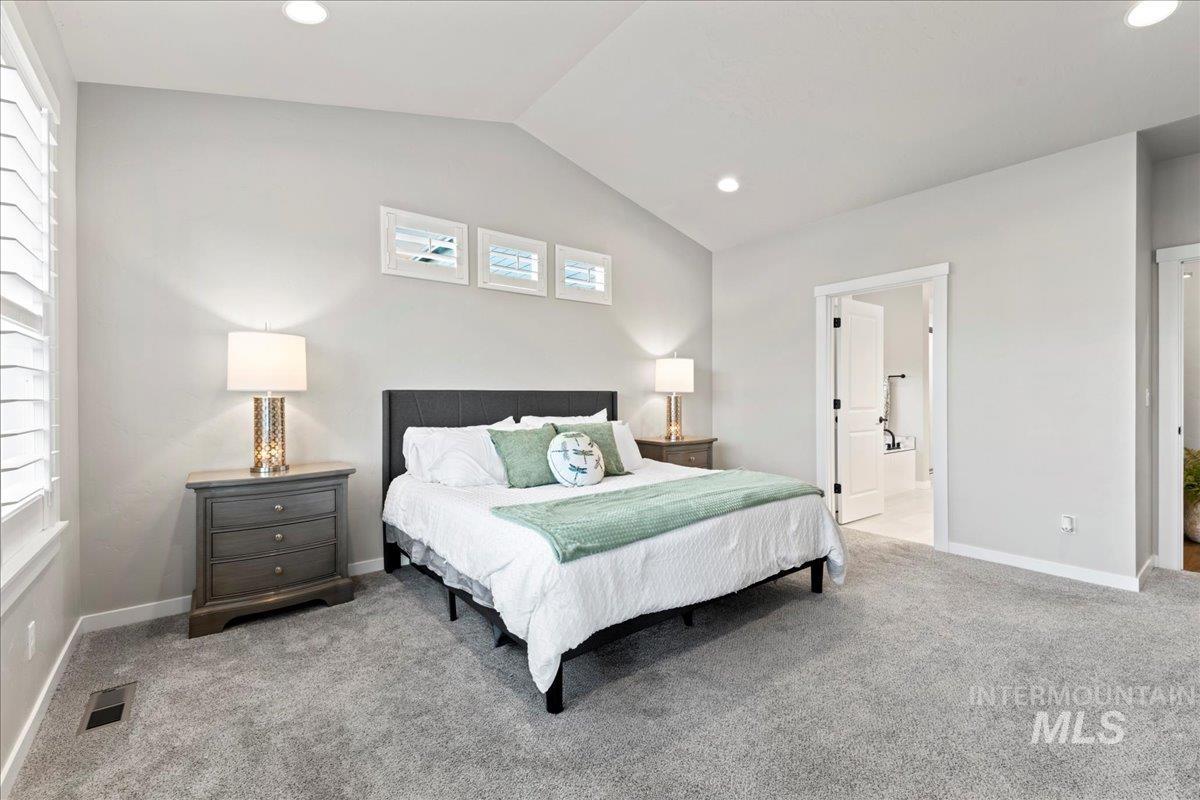 Bedroom with vaulted ceiling, light carpet, recessed lighting, and connected bathroom