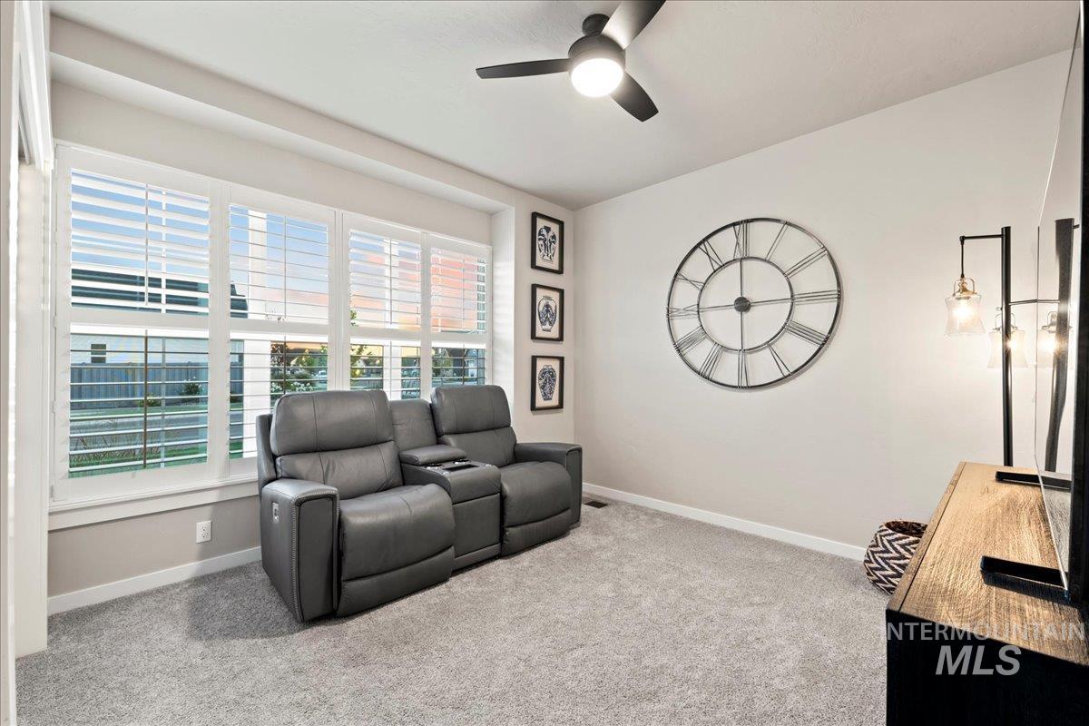 Carpeted living area featuring baseboards and a ceiling fan