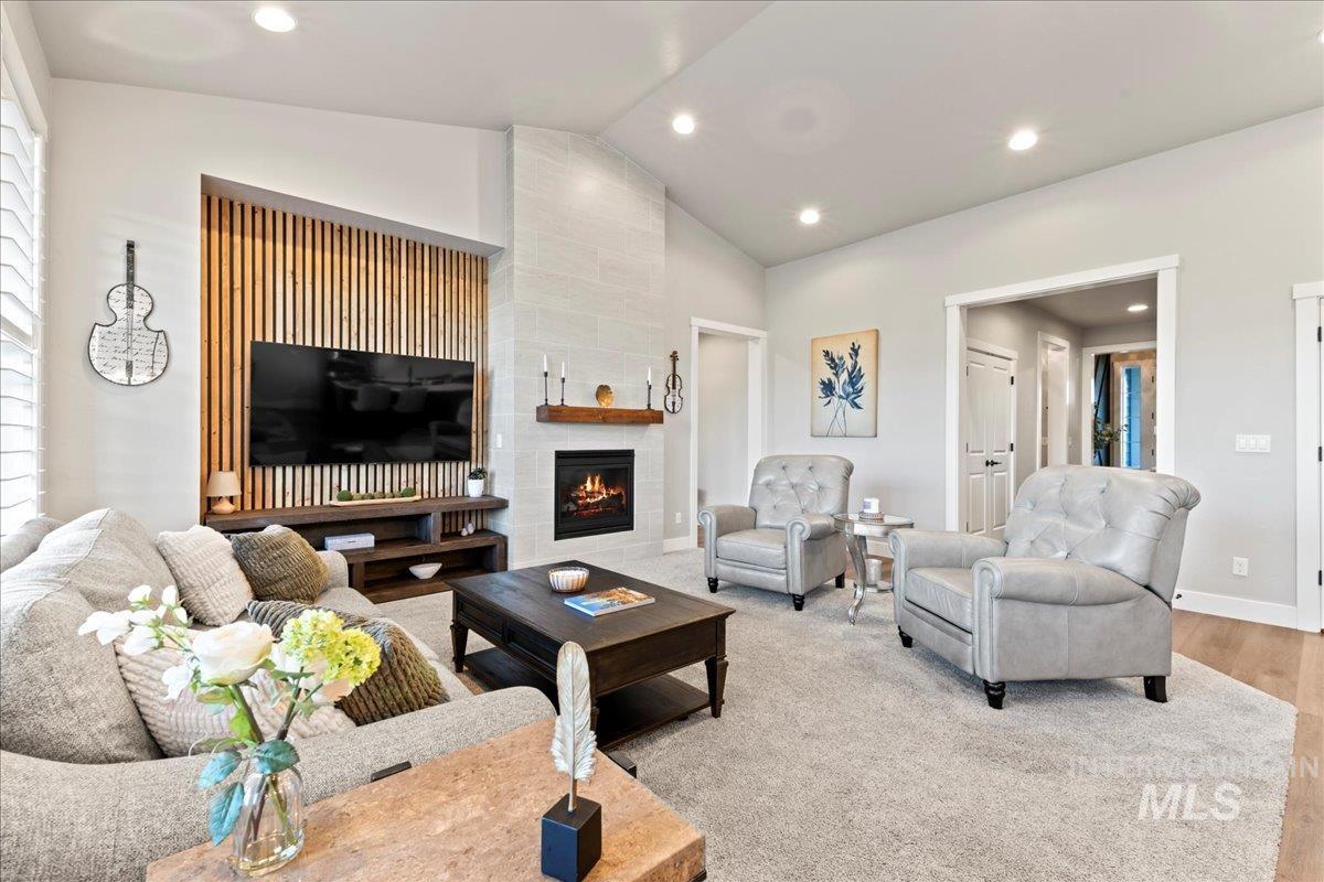 Living area with lofted ceiling, a tiled fireplace, recessed lighting, and wood finished floors