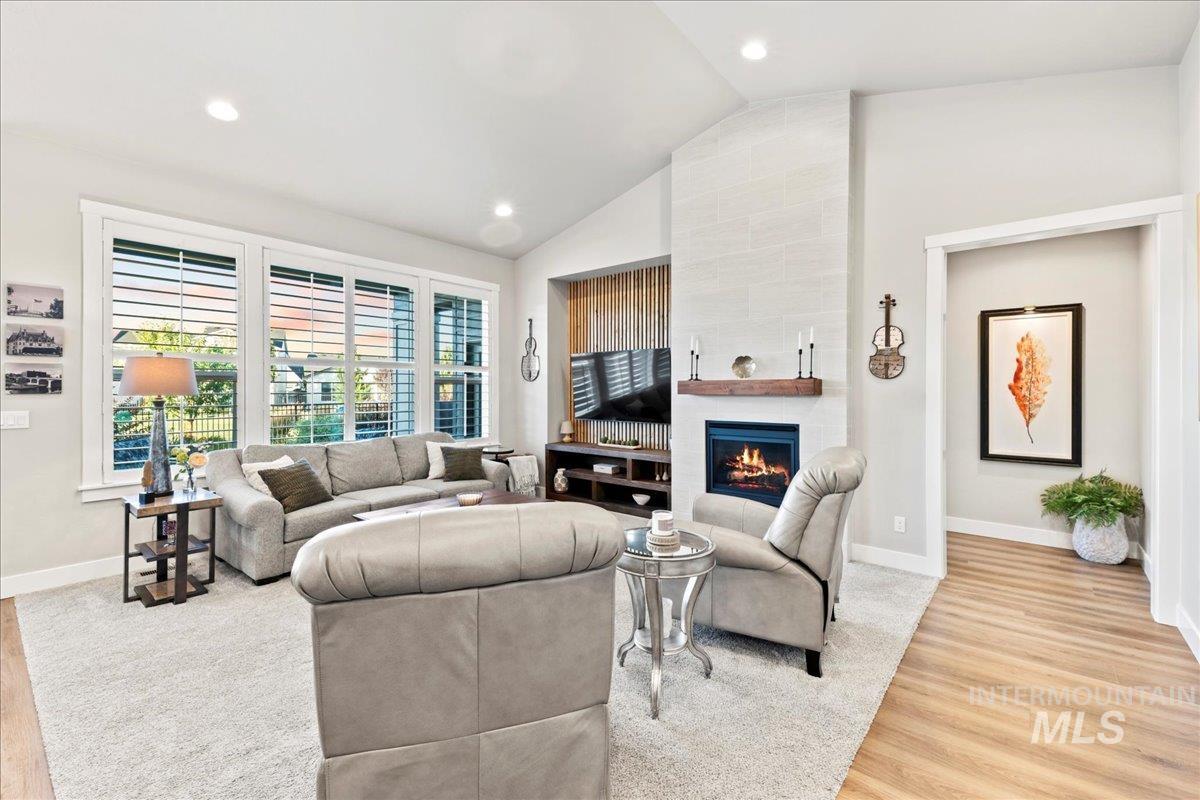 Living room featuring a fireplace, recessed lighting, light wood finished floors, and high vaulted ceiling