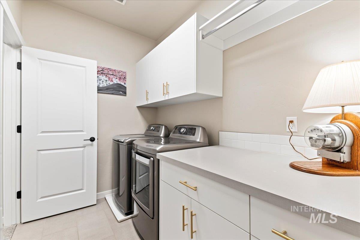 Laundry room with cabinet space, washing machine and clothes dryer, and light tile patterned flooring