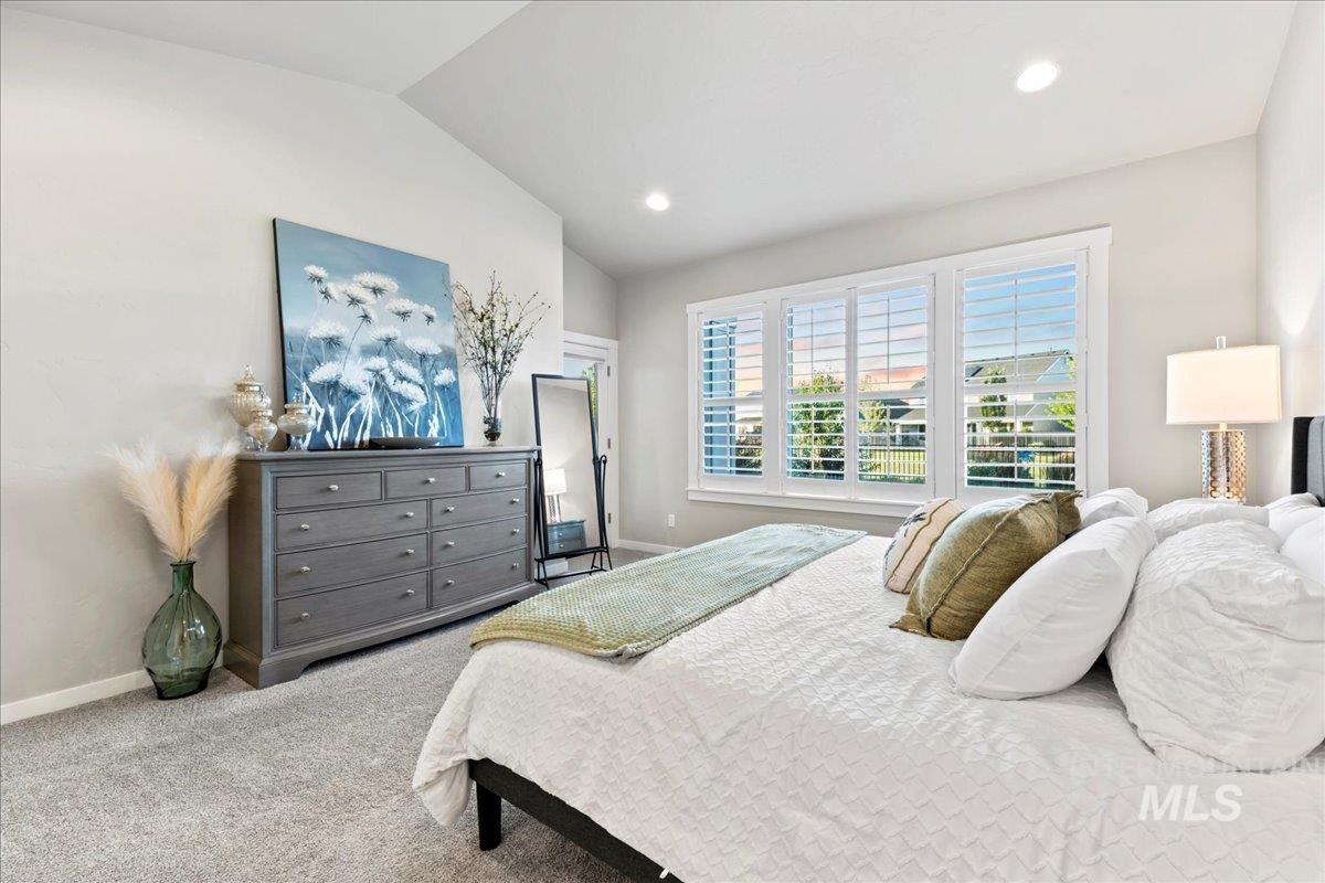 Carpeted bedroom with vaulted ceiling and recessed lighting