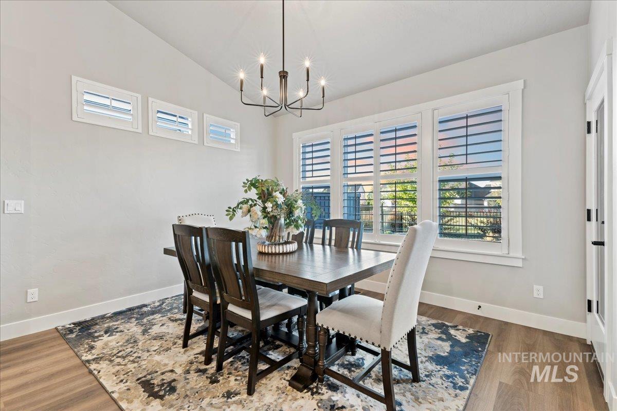Dining room with wood finished floors, a chandelier, and lofted ceiling