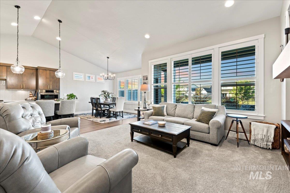 Living room featuring high vaulted ceiling, a chandelier, light wood-style flooring, and recessed lighting