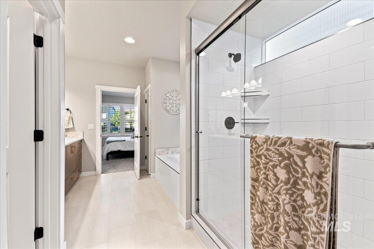 Bathroom with ensuite bathroom, a stall shower, vanity, recessed lighting, and light tile patterned floors