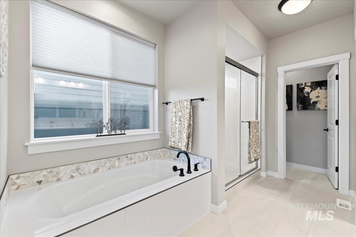 Full bathroom featuring a stall shower, a garden tub, and light tile patterned flooring