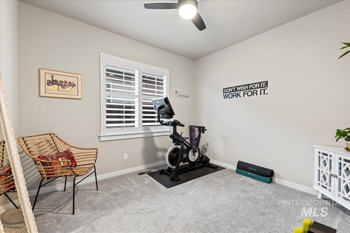 Exercise room featuring light carpet and ceiling fan
