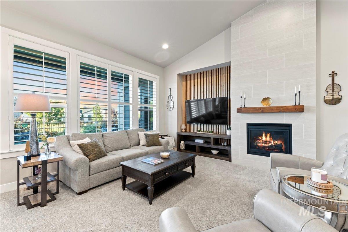 Carpeted living room featuring a tile fireplace, vaulted ceiling, and recessed lighting