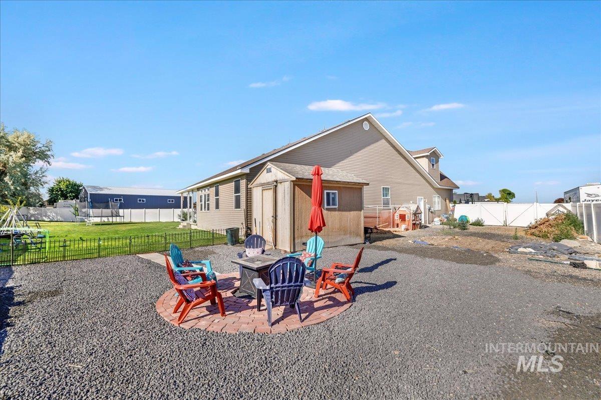 Rear view of property with a fire pit, a shed, a fenced backyard, and a patio
