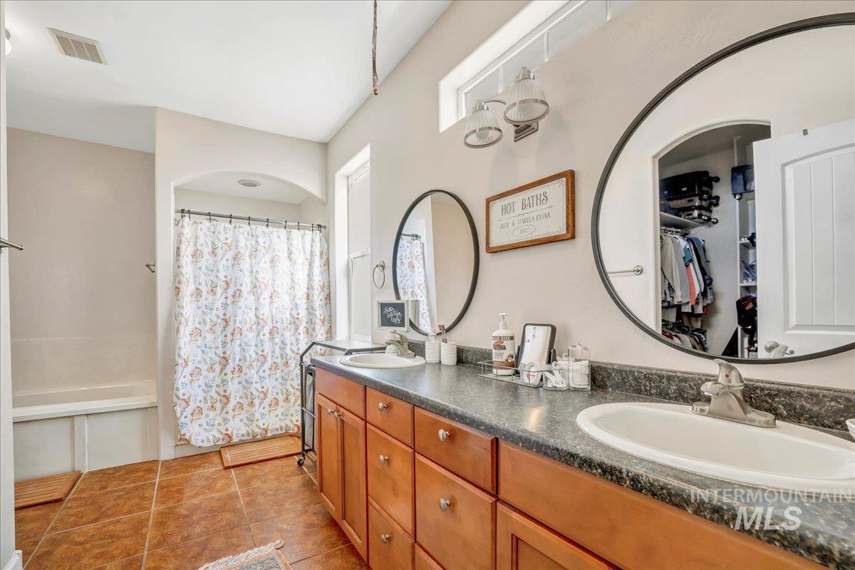 Full bathroom featuring double vanity and shower / tub combo