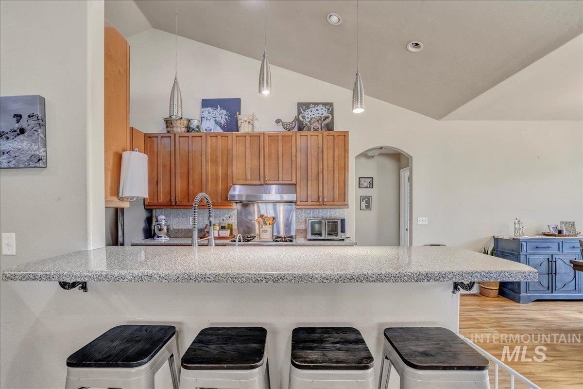 Kitchen with lofted ceiling, a peninsula, arched walkways, a kitchen breakfast bar, and decorative backsplash
