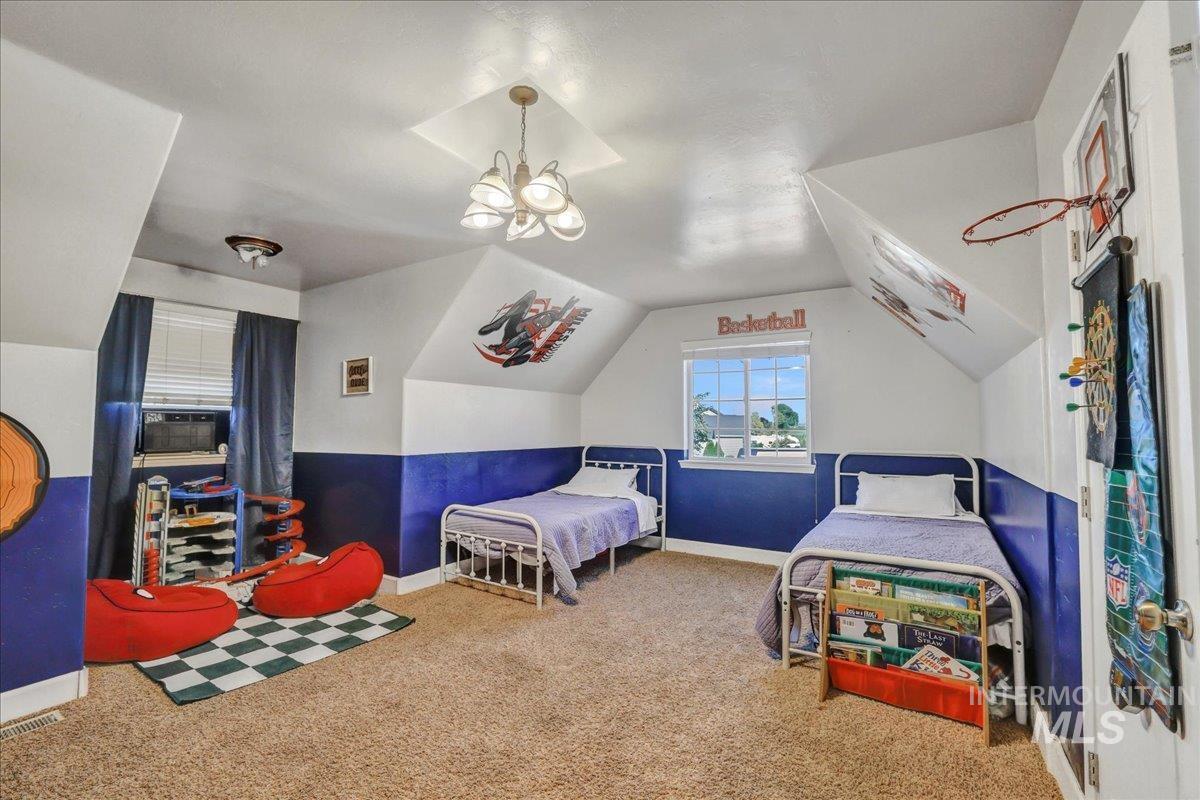 Bedroom featuring carpet floors, lofted ceiling, and a chandelier