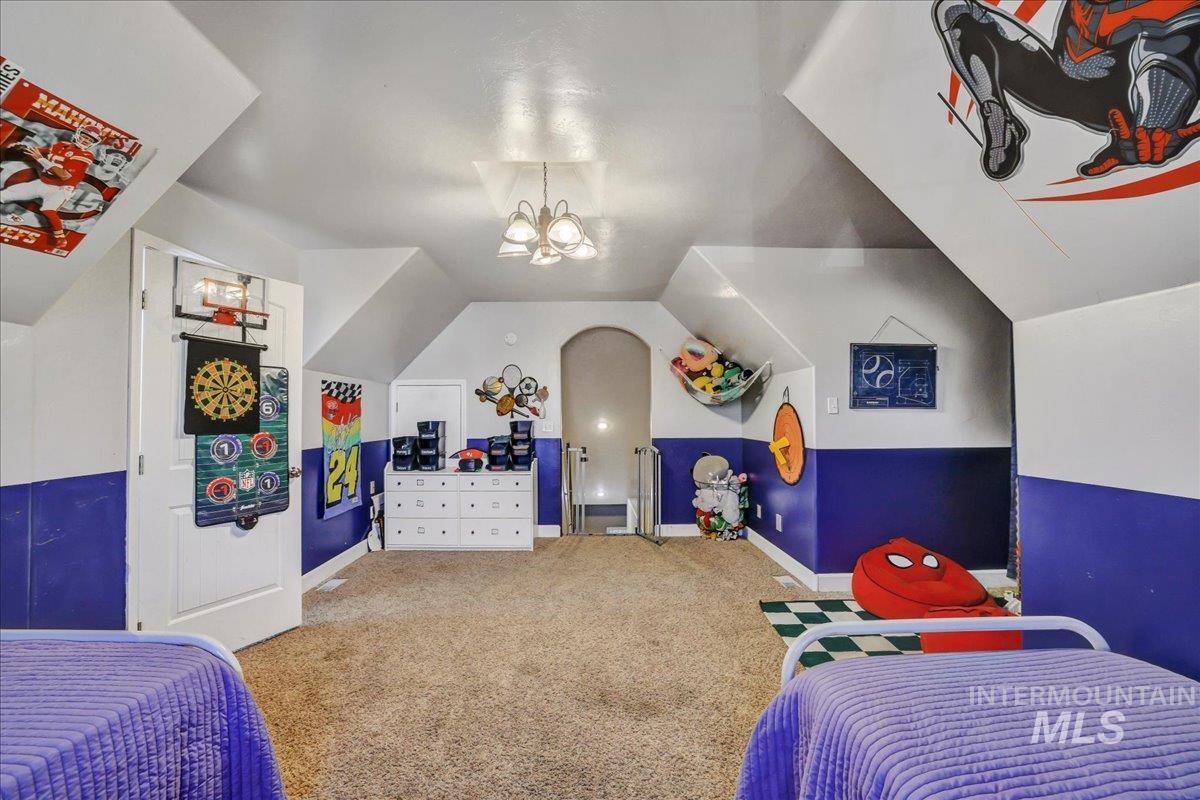 Bedroom with carpet, vaulted ceiling, and a chandelier