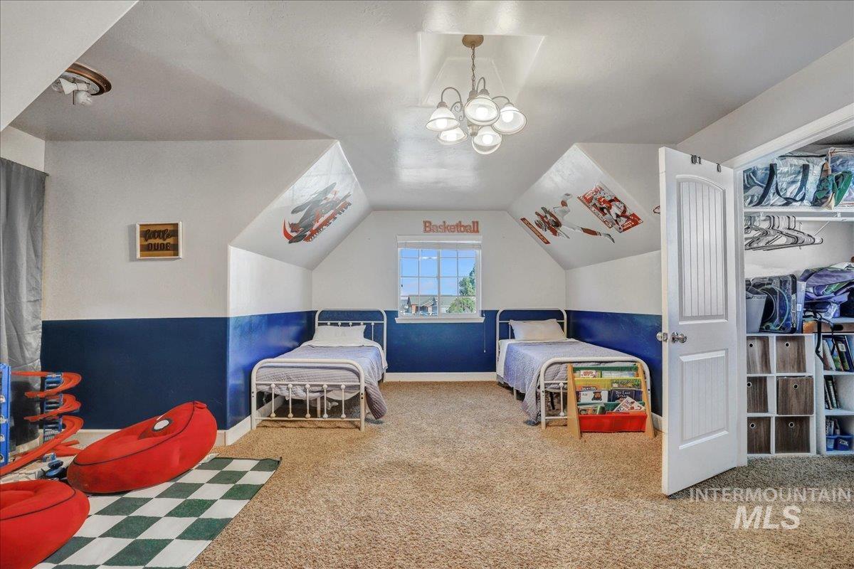 Carpeted bedroom featuring vaulted ceiling and a chandelier