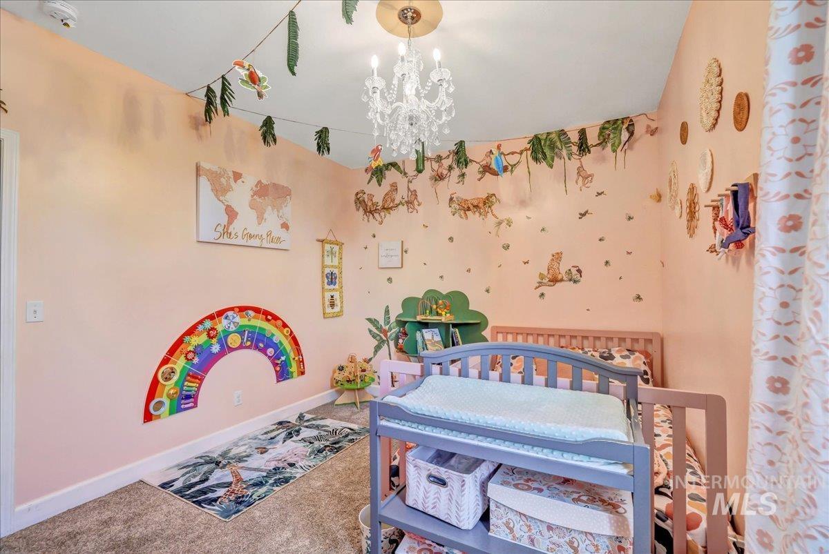 Carpeted bedroom featuring a chandelier and baseboards
