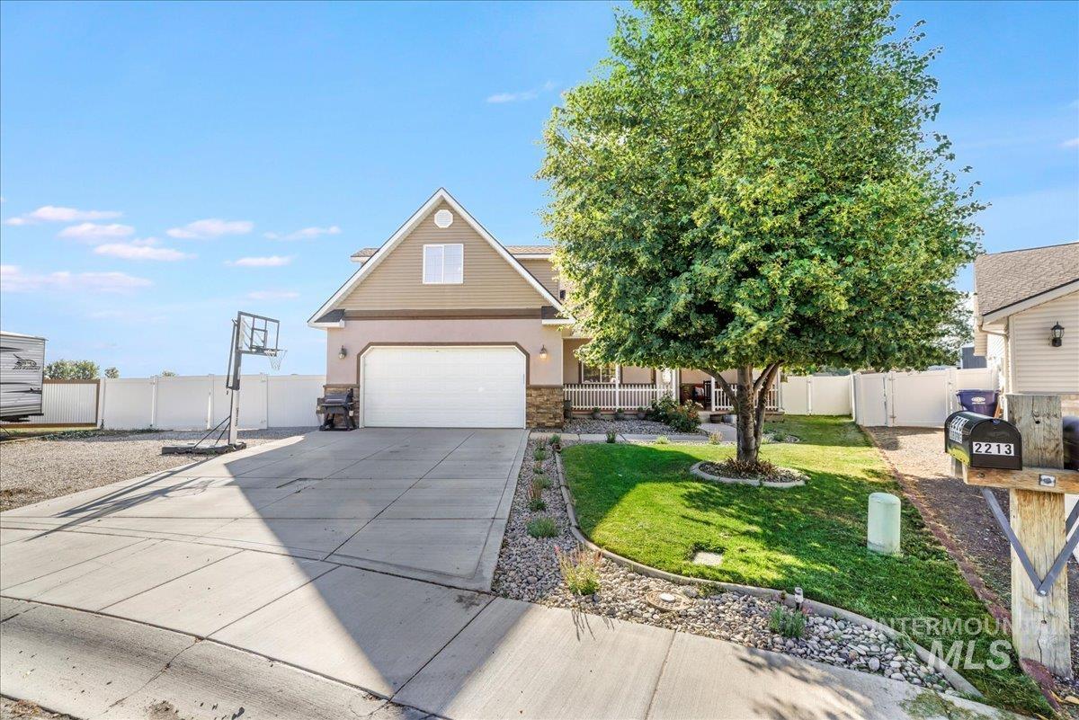 View of front of property with driveway, stone siding, a garage, and stucco siding