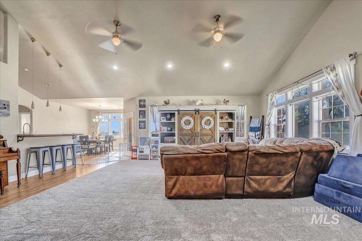 Living area featuring a ceiling fan, plenty of natural light, a chandelier, high vaulted ceiling, and recessed lighting