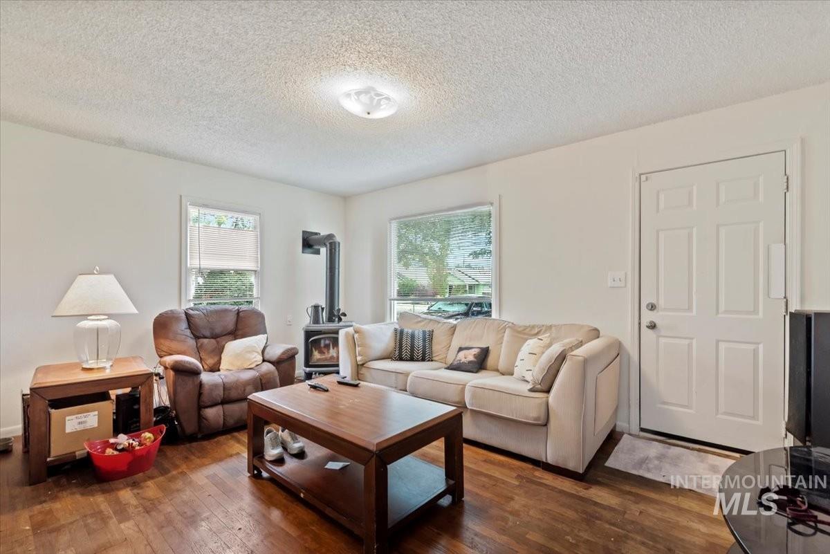 Living room with a wood stove, dark wood finished floors, and a textured ceiling