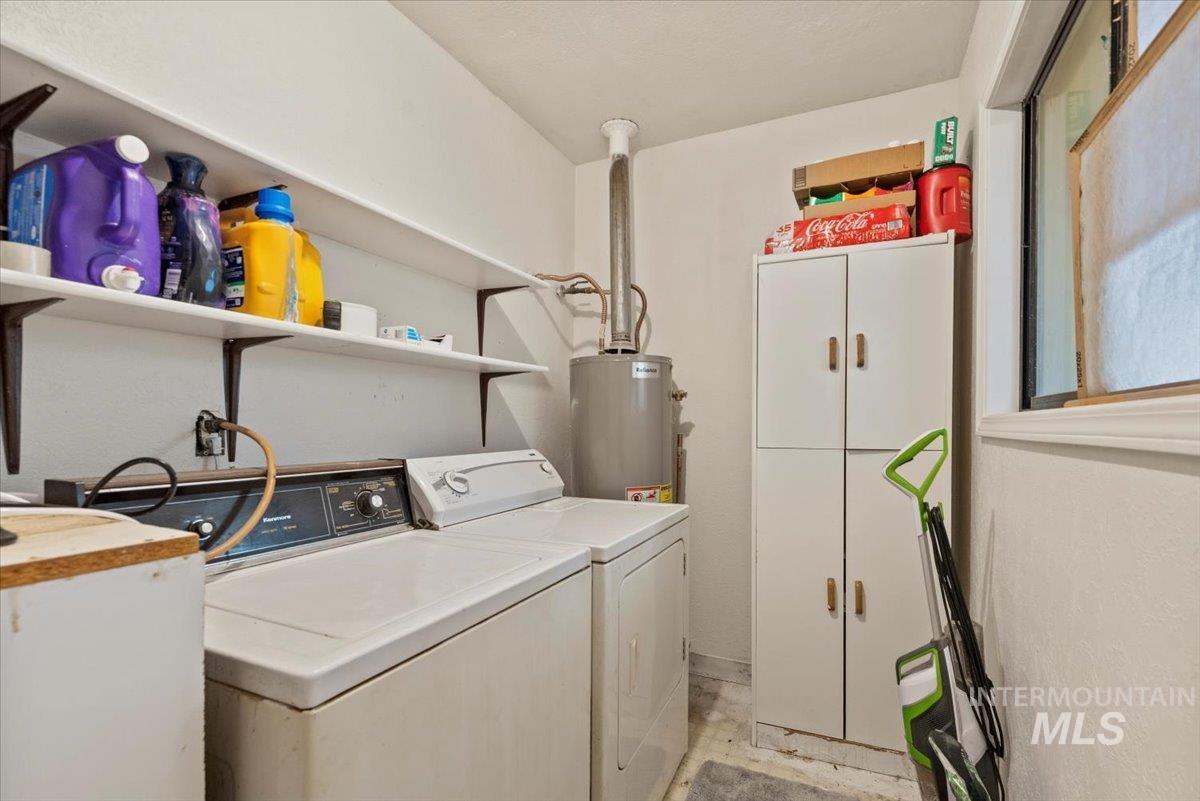 Washroom featuring washer and clothes dryer, cabinet space, and gas water heater