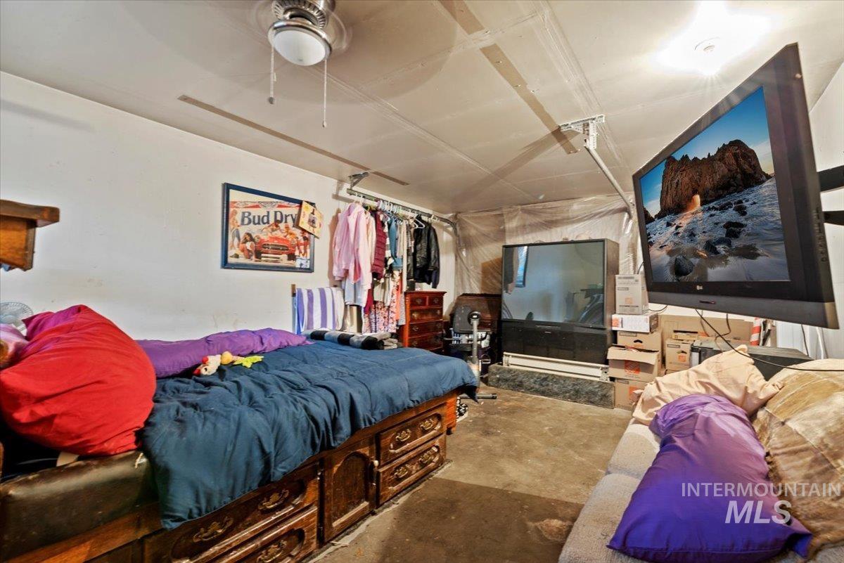 Bedroom featuring a ceiling fan, concrete flooring, and a baseboard radiator