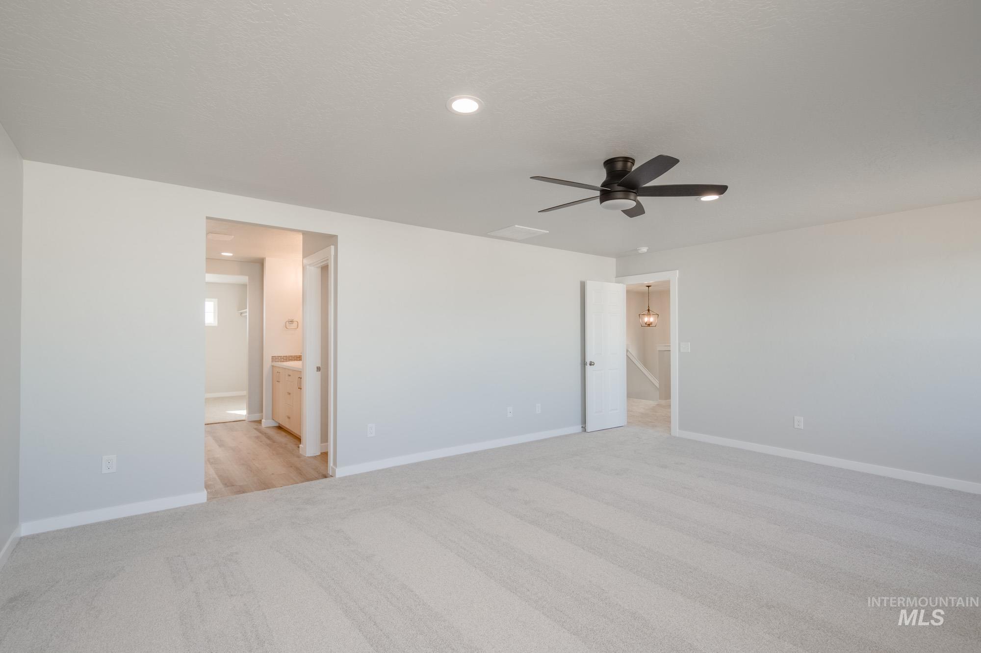 Unfurnished bedroom with light carpet, ceiling fan, ensuite bathroom, and recessed lighting