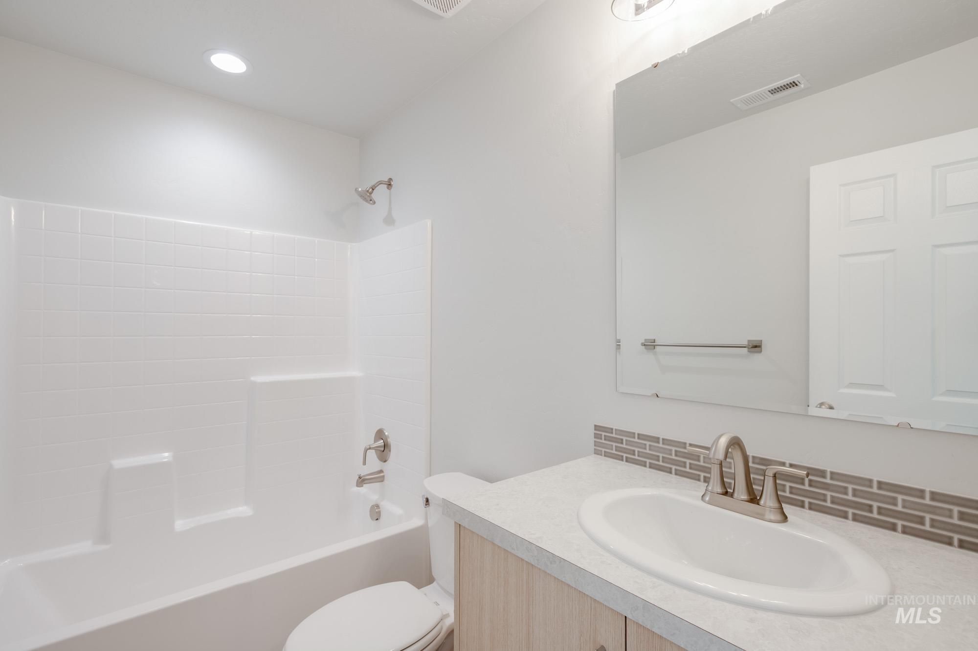 Bathroom with shower / bath combination, vanity, and backsplash