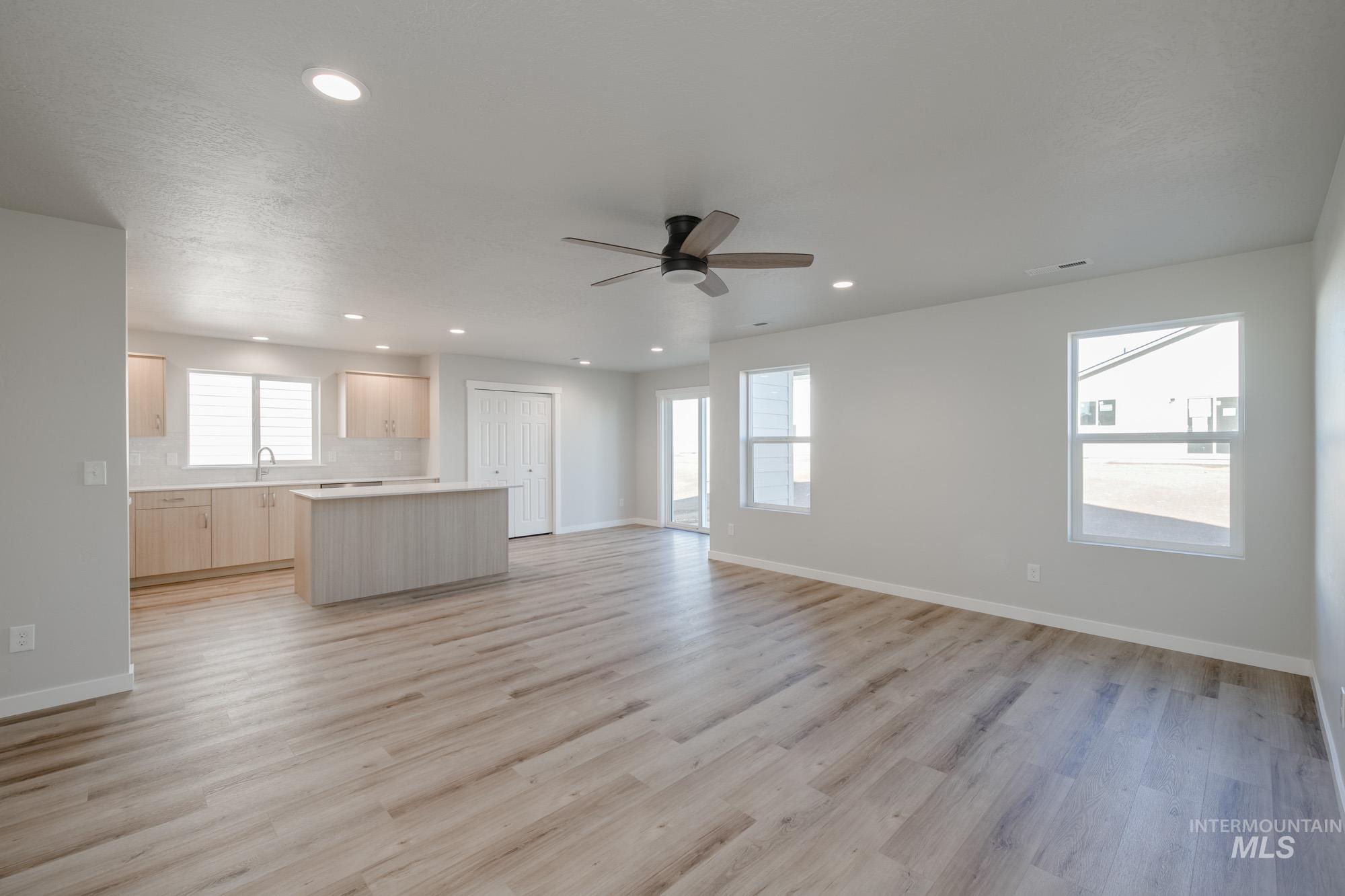 Unfurnished living room with light wood-style flooring, a ceiling fan, and recessed lighting