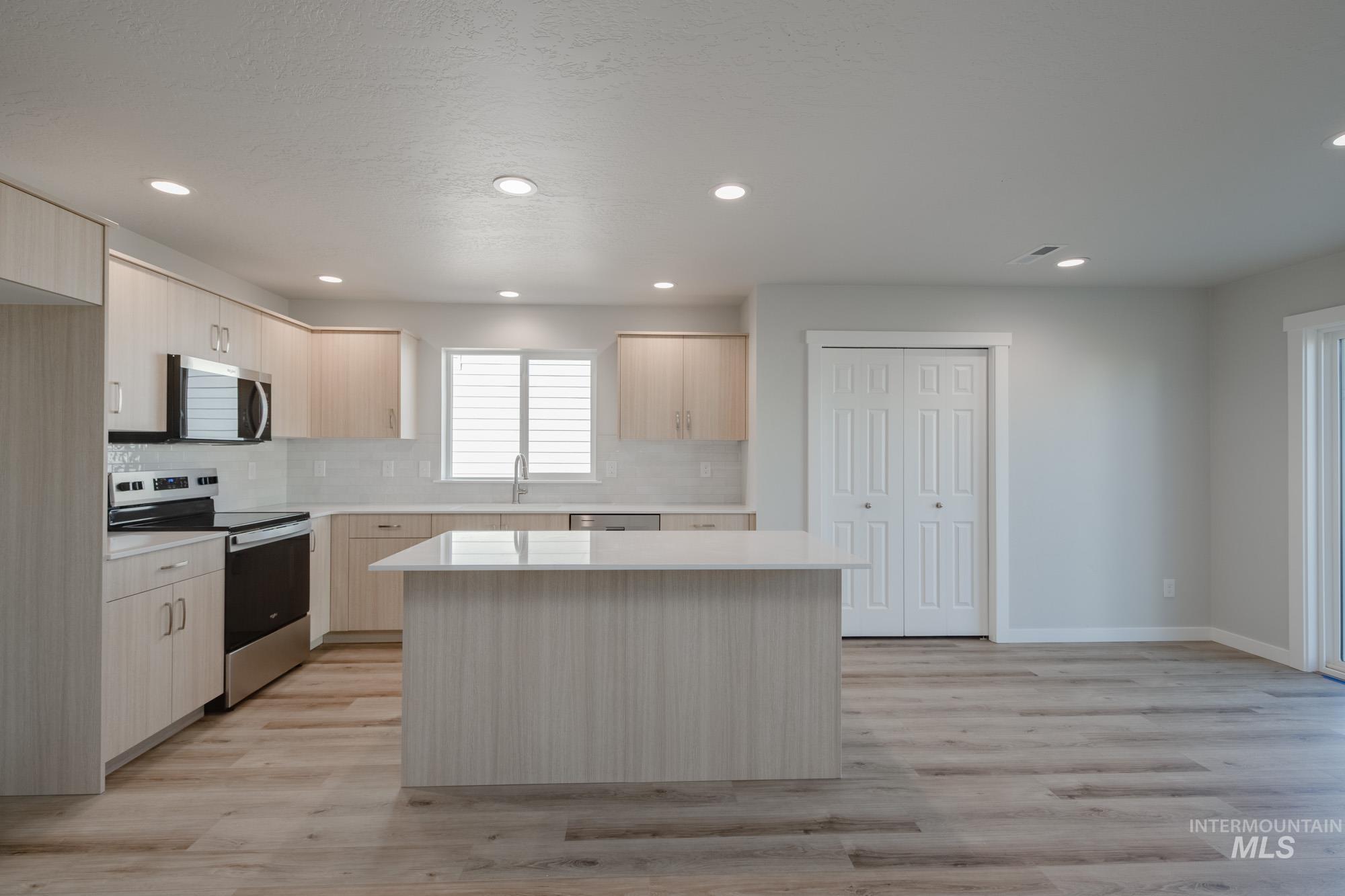 Kitchen featuring light brown cabinets, appliances with stainless steel finishes, modern cabinets, light wood finished floors, and recessed lighting