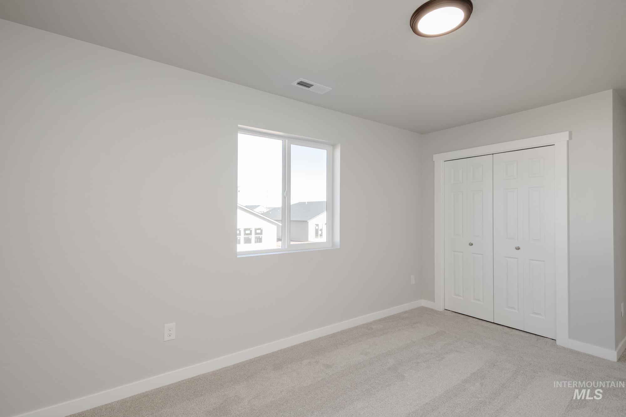 Unfurnished bedroom with light carpet and a closet