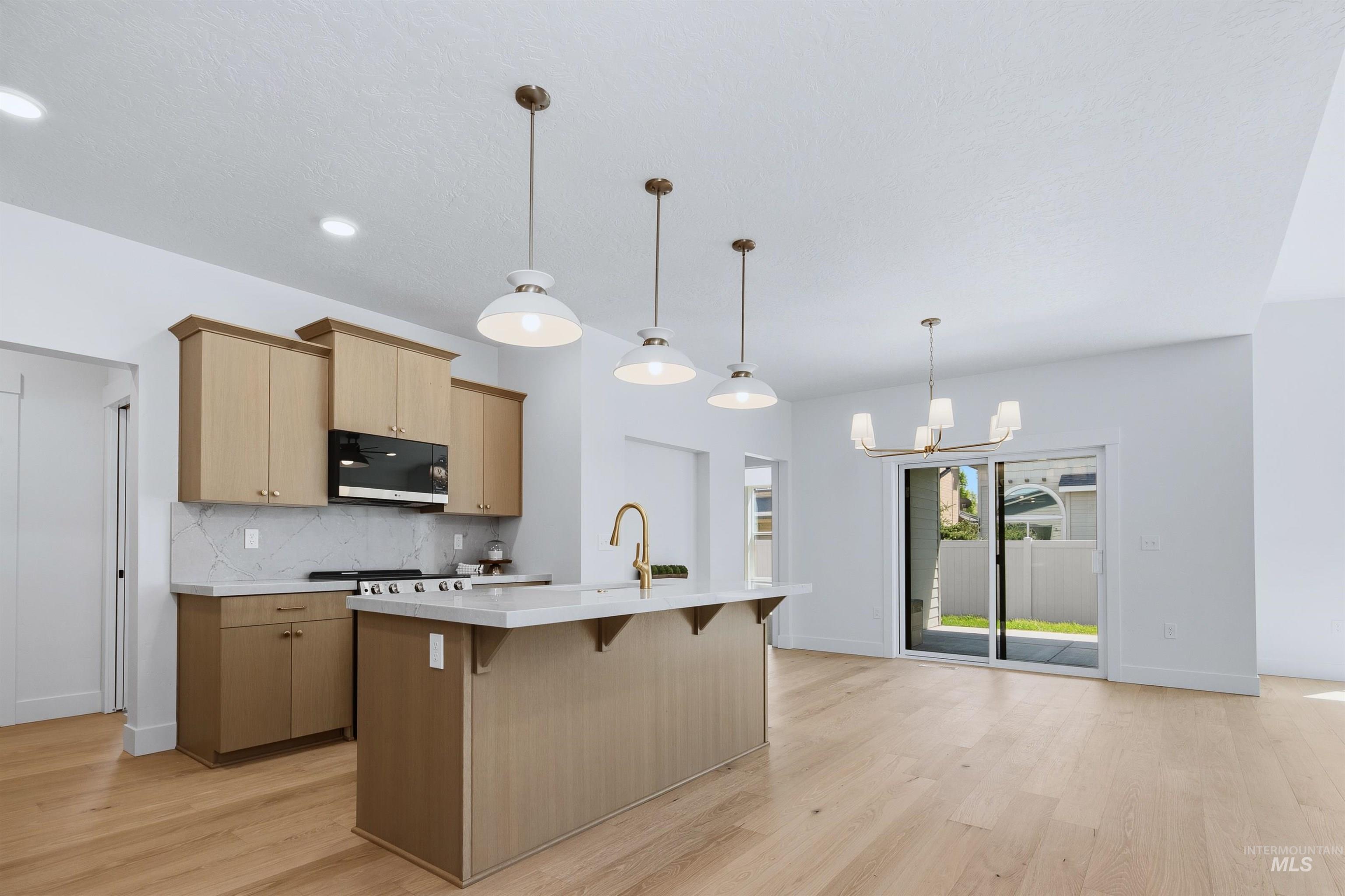 Modern kitchen featuring light wood-finish cabinetry, white countertops, and a white tile backsplash