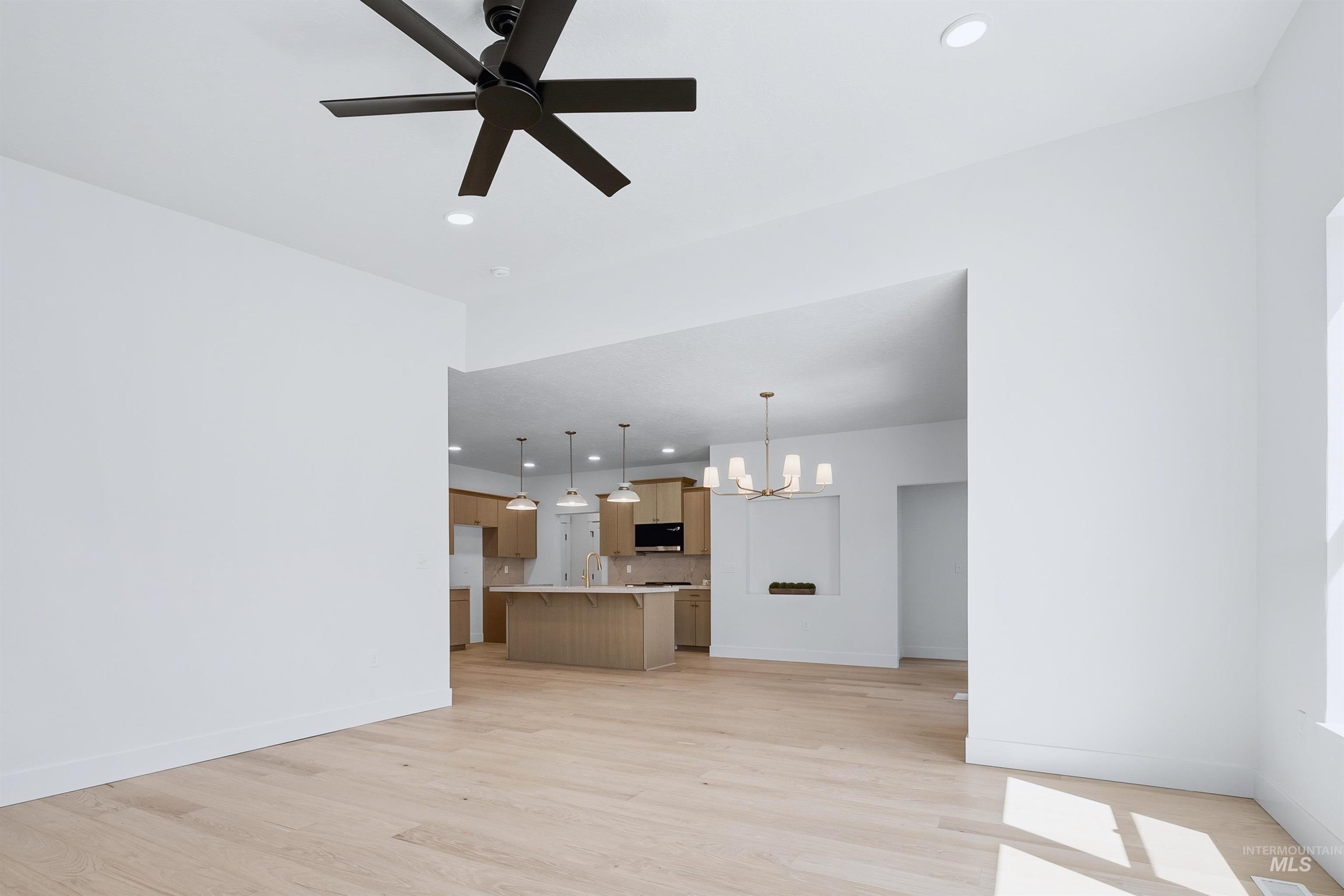 Open-concept living area featuring light wood-finish flooring, a contemporary ceiling fan, and recessed lighting