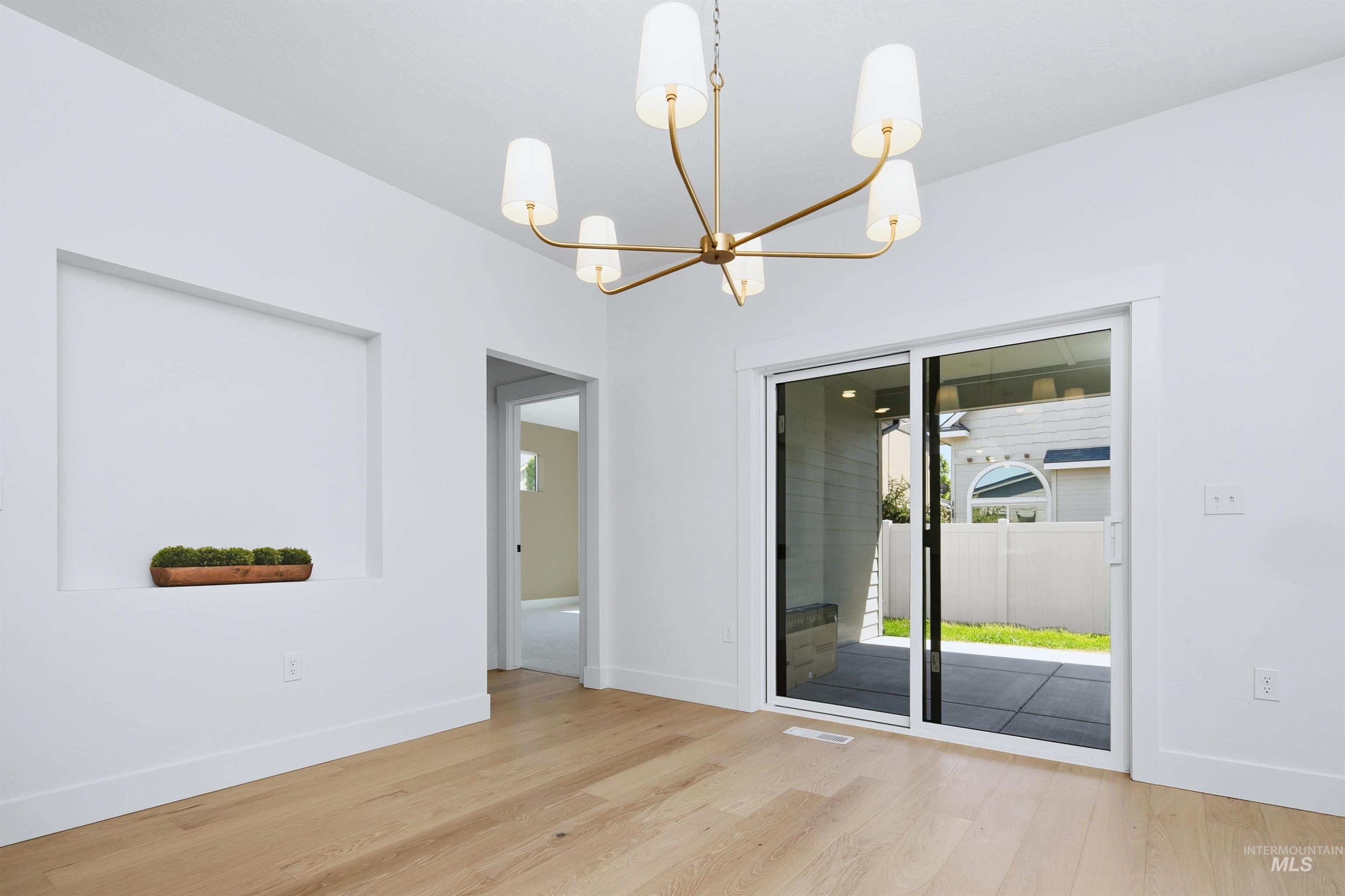Recessed wall niche, light wood-finish flooring, and a multi-arm chandelier with white cone shades
