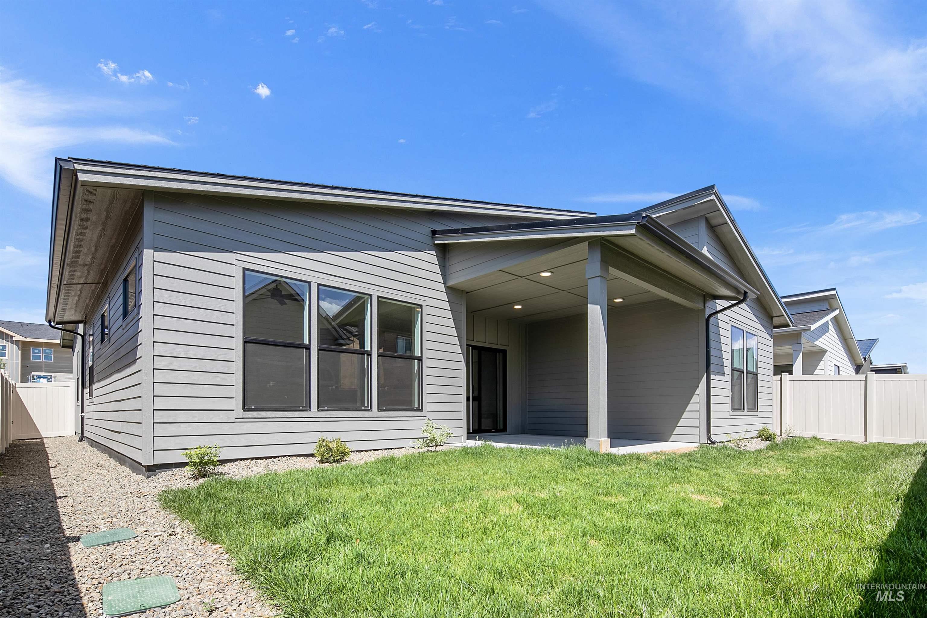 Rear exterior featuring a covered patio with recessed lighting, a sliding glass door, and a manicured lawn
