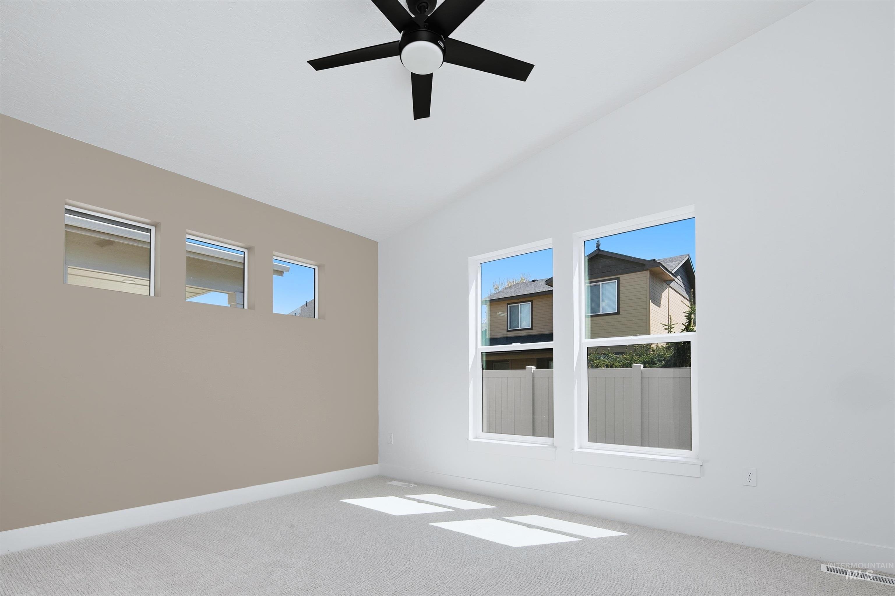 Bright room with a neutral accent wall and vaulted ceiling