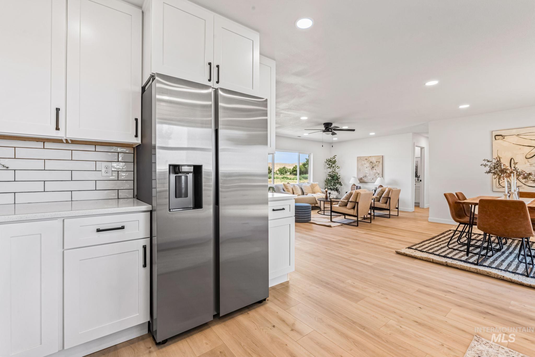 Kitchen with stainless steel refrigerator with ice dispenser, white cabinets, recessed lighting, and light wood-style flooring