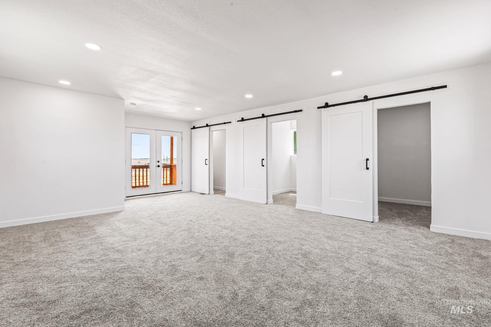 Unfurnished bedroom featuring recessed lighting, a barn door, light carpet, access to exterior, and french doors