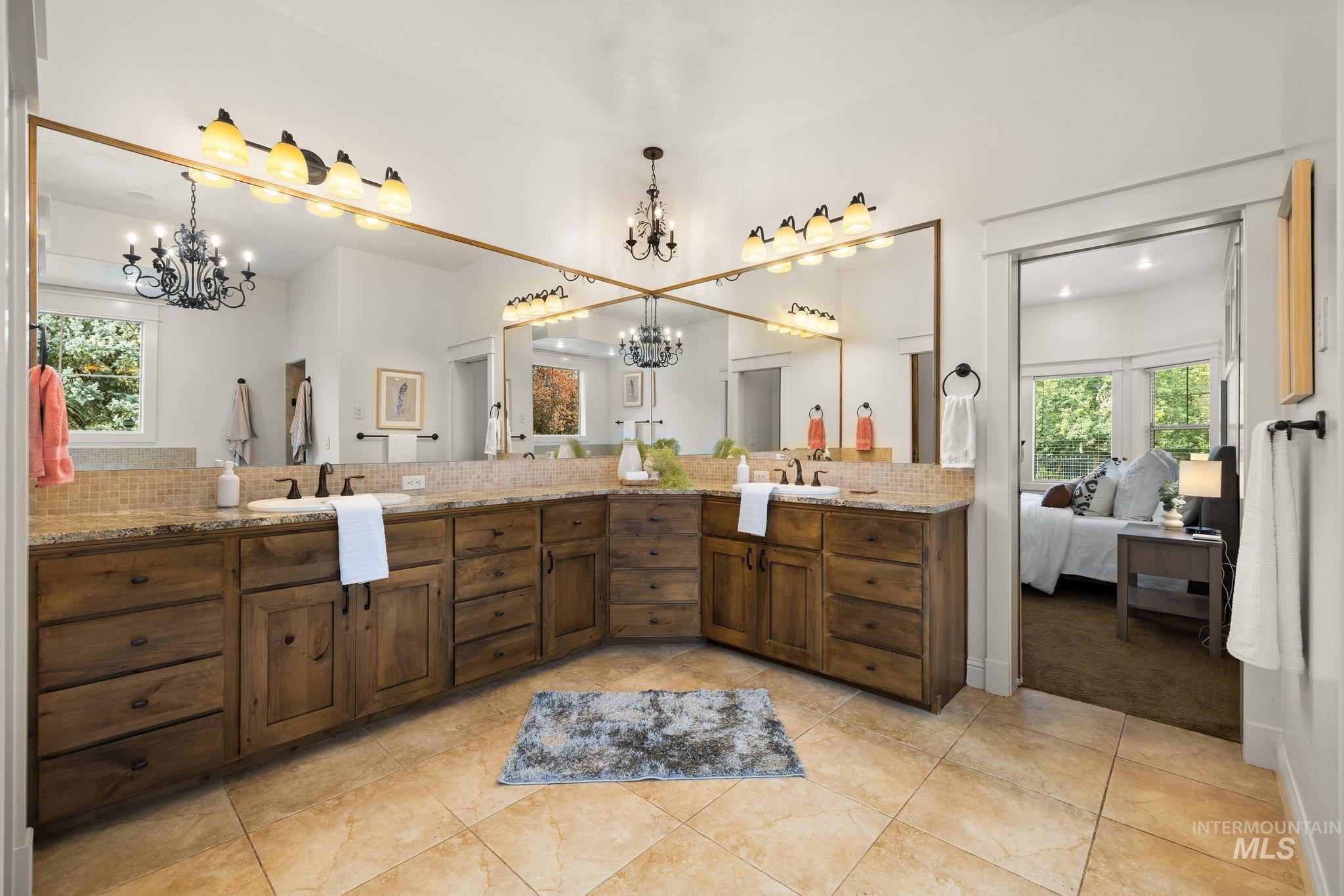 Bathroom featuring a chandelier, plenty of natural light, tasteful backsplash, and double vanity
